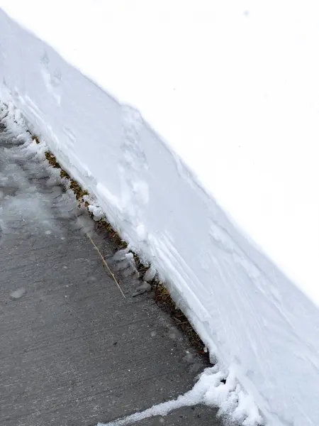 きれいに覆われた歩道が厚い雪の毛布を通って切断され 原始の白い障壁に対する厳しいコントラストを明らかにします — ストック写真