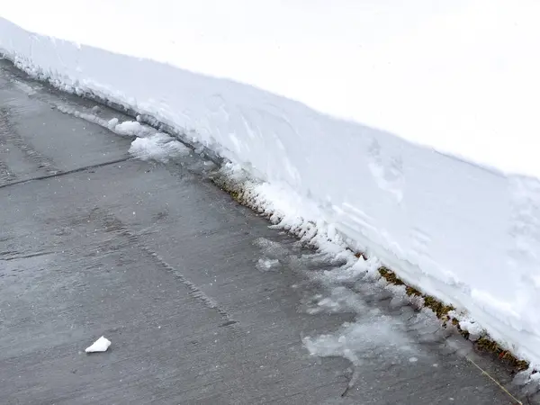 きれいに覆われた歩道が厚い雪の毛布を通って切断され 原始の白い障壁に対する厳しいコントラストを明らかにします — ストック写真