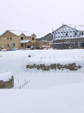Castle Rock, Colorado, USA-March 16, 2024-Fresh snowfall gently covers a new suburban neighborhood under construction, where the emerging structures await completion, nestled in a wintery setting. clipart