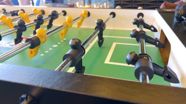 Dostça bir maça hazırlanan langırt masasında, figürler sıraya dizilmiş ve oynamaya hazır, parlayan bir şöminenin arka planına kurulmuş, rahat bir eğlence ortamı yaratıyor. Sahne sıcaklığı davet eder ve...