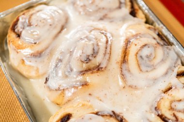 Fırından yeni çıkmış, tarçınlı çörek silikon bir hasırın üzerinde serinliyor, kremaları mutfak ışıklarının altında parlıyor..