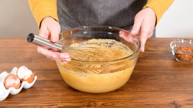 Bardak karıştırma kabında, büyük bir el çırpma ustalıkla lezzetli zencefilli kek ve karamel kremalı pasta malzemelerini karıştırır..