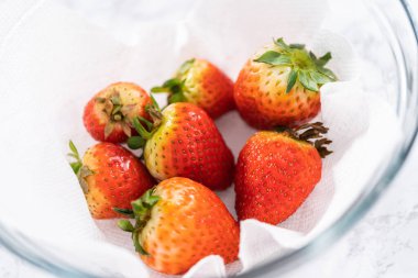 Taze yıkanmış ve kurutulmuş çilekler kağıt havluyla kaplı cam bir kasede dikkatlice düzenlenir. Atıştırmaya ya da daha fazla kullanılmaya hazır hale getirilir..