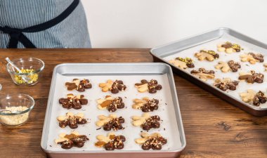 Çikolataya batırılmış ve fındık ezmesi ile süslenmiş kar tanesi şeklindeki kesme şekerli kurabiyeler yaratmak. Parşömen üzerinde zarif bir şekilde sunulmuş..