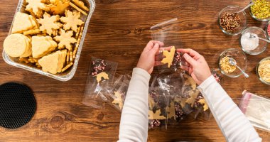 Dikkatlice paketlenmiş Noel kurabiyeleri, çikolataya batırılmış ve şeffaf selofan ambalajla sunulmuş, bayram hediyesi olarak mükemmel..