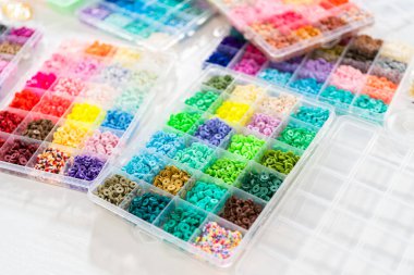 Beyaz bir masaya yerleştirilmiş çeşitli kil boncuk kutuları yaratıcı çocukların el sanatları projesini bekliyor..