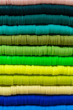 Beyaz bir masadaki renklere göre düzenlenmiş canlı bir kil boncuk koleksiyonu genç zanaatkarlara kendi eşsiz bileziklerini yapmaları için ilham vermeye hazır..