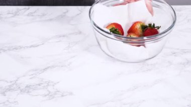 Çilekler, yeni yıkanmış ve kurutulmuş, cam bir kasede güzelce depolanmış kağıt havluyla kaplanmış ve tazeliği korumak için plastikle kaplanmış..