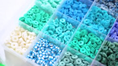 Renklere göre sıralanmış çeşitli kil boncukların yakın plan çekimleri, her boncuğu el yapımı ve mücevher yapımında eşsiz kılan desenleri ve desenleri vurguluyor..