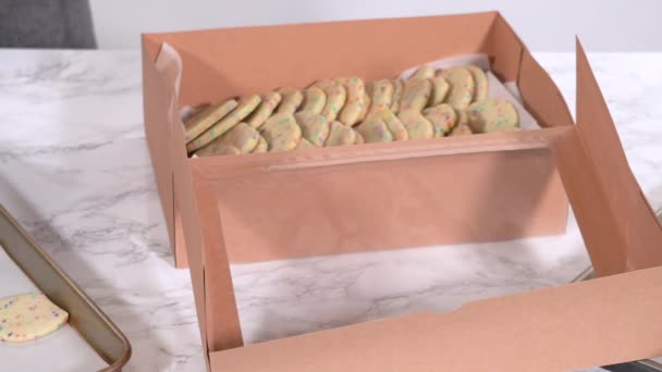 精密に 女性は慎重に砂糖クッキーを配置しています 生地混合スパイクでいっぱい 素朴な茶色の紙箱に — ストック動画
