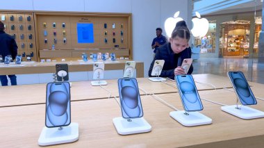 Denver, Colorado, ABD-23 Mart 2024-meraklı küçük kız Park Meadows Alışveriş Merkezi 'ndeki Apple Store' da sergilenen son iPhone modellerini inceliyor..