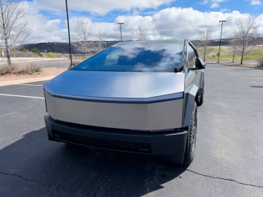 Denver, Colorado, ABD-28 Mart 2024-Tesla Cybertruck 'ın ön profili sergileniyor, fütüristik çizgileri ve sağlam tasarımı sergileniyor, açık hava parkında dinamik bir gökyüzü ile park edilmiş.
