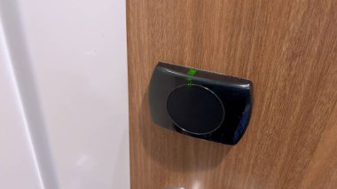 Otel odasının kapısının kilidini açmak için siyah anahtar kullanan bir misafirin yakın çekim görüntüsü modern otel erişim sistemlerinin güvenlik ve rahatlığını gösteriyor..