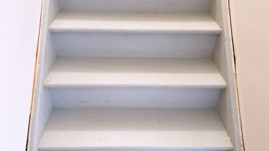 Temiz çizgileri ve minimalist tasarımı ile karakterize edilmiş, bir evin bodrumuna inen sade, beyaz bir merdiven manzarası.