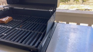 Açık hava ızgarasında ızgara izleri olan birkaç kalın biftek, güneşli bir barbekü gününün özünü yakalıyor..