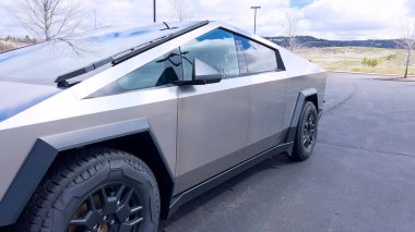 Bir Tesla Siber Traktörü, banliyö sokağında park halindeki kendine özgü, fütüristik tasarımı ve metalik vücuduyla öne çıkıyor. Gelişmiş otomotiv teknolojisinin günlük yaşamla olan karışımını gösteriyor..