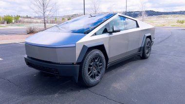 Bir Tesla Siber Traktörü, banliyö sokağında park halindeki kendine özgü, fütüristik tasarımı ve metalik vücuduyla öne çıkıyor. Gelişmiş otomotiv teknolojisinin günlük yaşamla olan karışımını gösteriyor..