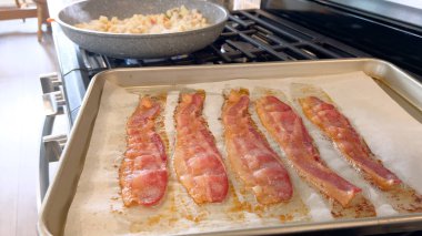 Bu görüntüde, parşömen astarlı fırında pişirilmiş domuz pastırması şeritleri var. Çekici altın-kahverengi rengi ve çıtır çıtır aromasını yakalıyor..