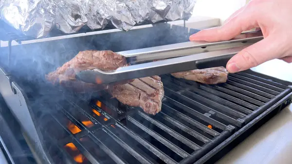 Person Uses Tongs Flip Juicy Steaks Grill Flames Licking Meat Stock Picture
