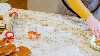 Modern bir mutfaktaki zarif mermer tezgahın üzerine zencefilli kurabiye hamuru sermek için ayarlanabilir bir merdane kullanmak, bayram pişirme şenliğine hazırlanmak....