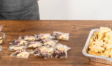 Dikkatlice paketlenmiş Noel kurabiyeleri, çikolataya batırılmış ve şeffaf selofan ambalajla sunulmuş, bayram hediyesi olarak mükemmel..