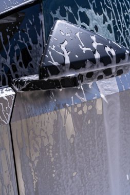 Denver, Colorado, ABD-5 Mayıs 2024 Bu görüntü, bir araba yıkama sırasında sabun köpüğüyle kaplanmış Tesla Siber Kamyon yan aynasının yakın görüntüsünü yakalıyor.