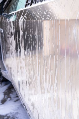 Denver, Colorado, ABD-5 Mayıs 2024-Bu görüntü sabunlu suyun bir yıkama sırasında bir Tesla Cybertruck 'ın metalik, açısal tarafından güzel bir şekilde akışını yakalar. Yakın çekim gösterileri, şık çizgiler ve...