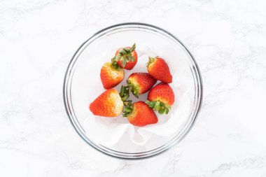 Taze yıkanmış ve kurutulmuş çilekler kağıt havluyla kaplı cam bir kasede dikkatlice düzenlenir. Atıştırmaya ya da daha fazla kullanılmaya hazır hale getirilir..