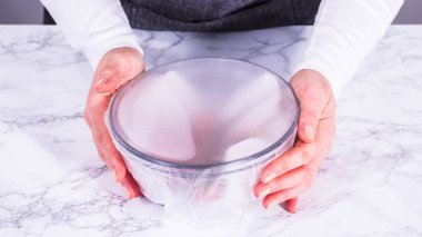 Çilekler, yeni yıkanmış ve kurutulmuş, cam bir kasede güzelce depolanmış kağıt havluyla kaplanmış ve tazeliği korumak için plastikle kaplanmış..