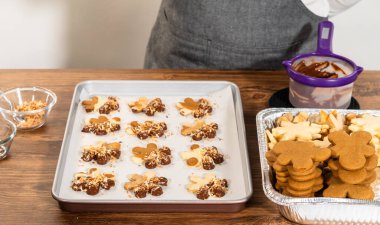 Zencefilli adam kurabiyeleri, çikolata soslu ayaklar, bol bol kızarmış hindistan cevizi talaşı serpiştirilmiş, parşömen kağıdına ustalıkla yerleştirilmiş..