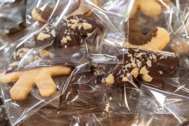 Dikkatlice paketlenmiş Noel kurabiyeleri, çikolataya batırılmış ve şeffaf selofan ambalajla sunulmuş, bayram hediyesi olarak mükemmel..