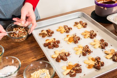 Çikolataya batırılmış ve fındık ezmesi ile süslenmiş kar tanesi şeklindeki kesme şekerli kurabiyeler yaratmak. Parşömen üzerinde zarif bir şekilde sunulmuş..