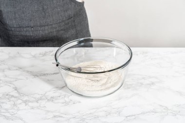 Kuru malzemeleri, büyük bir bardakta çırpma kabıyla karıştırarak Amerikan bayrağı mini kekleri pişiriyor..