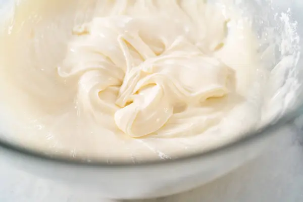 stock image Mixing ingredients in a large glass mixing bowl to make the cream cheese glaze.