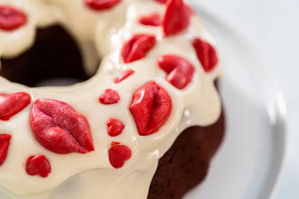 stock image Freshly baked red velvet bundt cake with chocolate lips and hearts over cream cheese glaze for Valentines Day.