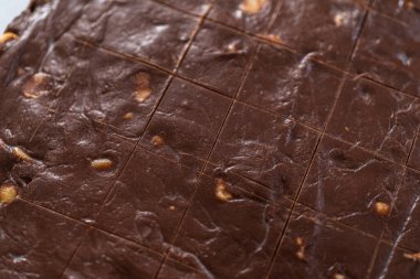 Küçük kare parçaları kesmek için tekerlek hamuru kesicisi kullanarak çikolatalı macadamia şekerlemesi yapmak.