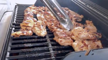 Salamura edilmiş tavuk butları küçük bir Weber ızgarasının ızgarasında cızırdar, havayı iştah açıcı bir koku ve hafif bir dumanla doldurur..