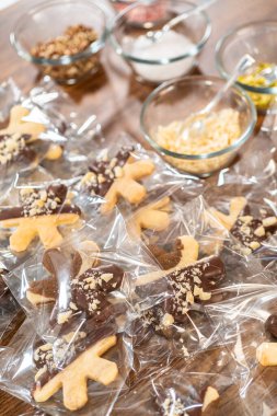 Dikkatlice paketlenmiş Noel kurabiyeleri, çikolataya batırılmış ve şeffaf selofan ambalajla sunulmuş, bayram hediyesi olarak mükemmel..