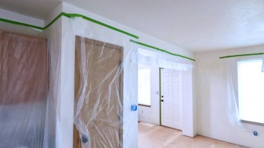 Tadilattan geçen bir mutfak, duvarlar ve tavan boyunca plastik çarşaflar ve maskeleme bantlarıyla kaplı dolaplar. Bu alan boyama ya da inşaat işleri için hazırlandı..