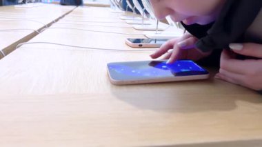 Denver, Colorado, ABD-9 Nisan 2024-10 yaşındaki bir kız dikkatle Apple Store 'daki bir stantta sergilenen yeni bir iPhone' u keşfediyor.