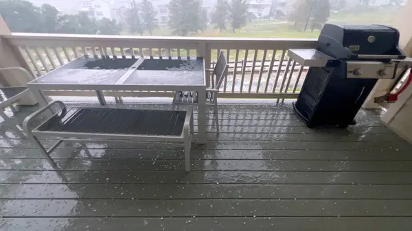 stock image Castle Rock, Colorado, USA-June 12, 2024-Slow motion-Image capturing a hail storm on a wooden deck, highlighting the impact of hail on patio furniture and the deck surface. Hailstones are visible