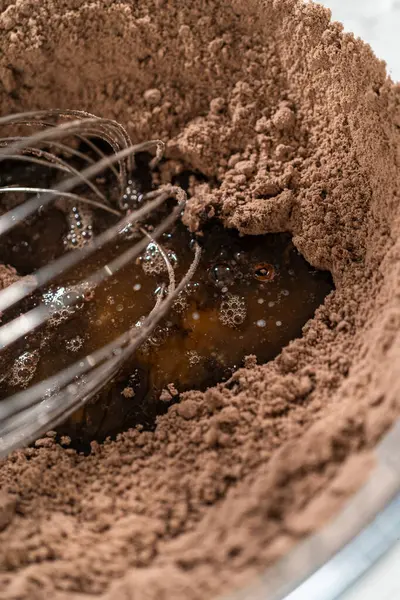 stock image In the process of creating mouthwatering chocolate cupcakes, the first step involves meticulously mixing the ingredients in a glass mixing bowl to make the perfect batter.