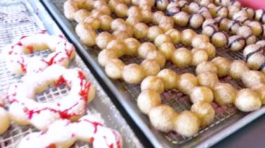 Vitrinler, metal tepsilerde çeşitli malzemelerle taze pişmiş mochi çörekleri, eşsiz şekillerini ve şekerli kaplamalarını vurguluyor..
