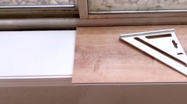 Tek bir vinil döşeme tahtası bir odanın kenarına dikkatlice yerleştirilir, uzay boşluklarının dokulu beyaz duvara tam olarak uymasını sağlar, bu da uzayın dönüşümünde bir adım olduğunu gösterir..