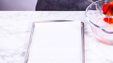 Sulu kırmızı çilekler, daha yeni yıkanmış, kabartma çarşafına serilmiştir, aşırı nemi emmek ve küfü önlemek için dikkatlice kağıt havlularla kaplanmıştır..