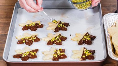 Çikolataya batırılmış ve çeşitli malzemeler serpiştirilmiş yıldız şeklinde tatil kurabiyeleri..