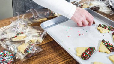 Dikkatlice paketlenmiş Noel kurabiyeleri, çikolataya batırılmış ve şeffaf selofan ambalajla sunulmuş, bayram hediyesi olarak mükemmel..