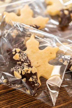 Dikkatlice paketlenmiş Noel kurabiyeleri, çikolataya batırılmış ve şeffaf selofan ambalajla sunulmuş, bayram hediyesi olarak mükemmel..