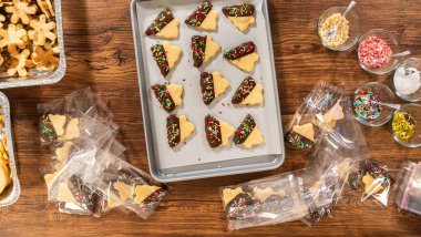 Dikkatlice paketlenmiş Noel kurabiyeleri, çikolataya batırılmış ve şeffaf selofan ambalajla sunulmuş, bayram hediyesi olarak mükemmel..