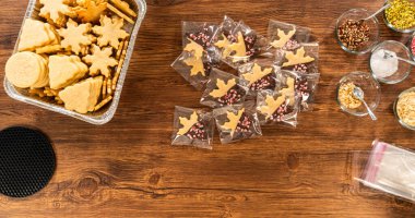 Dikkatlice paketlenmiş Noel kurabiyeleri, çikolataya batırılmış ve şeffaf selofan ambalajla sunulmuş, bayram hediyesi olarak mükemmel..